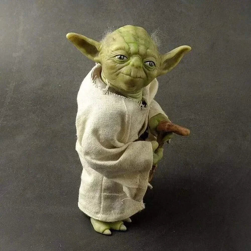 Green alien action figure in white robe holding a cane, collectible toy on gray background.