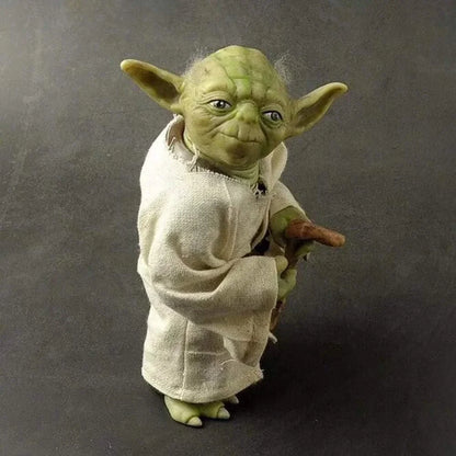Green alien action figure in white robe holding a cane, collectible toy on gray background.