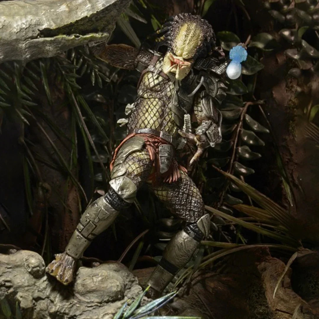 Predator action figure posed in a jungle setting with detailed armor and weapon.