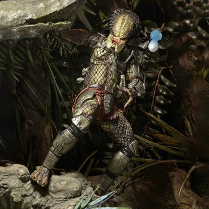 Predator action figure posed in a jungle setting with detailed armor and weapon.