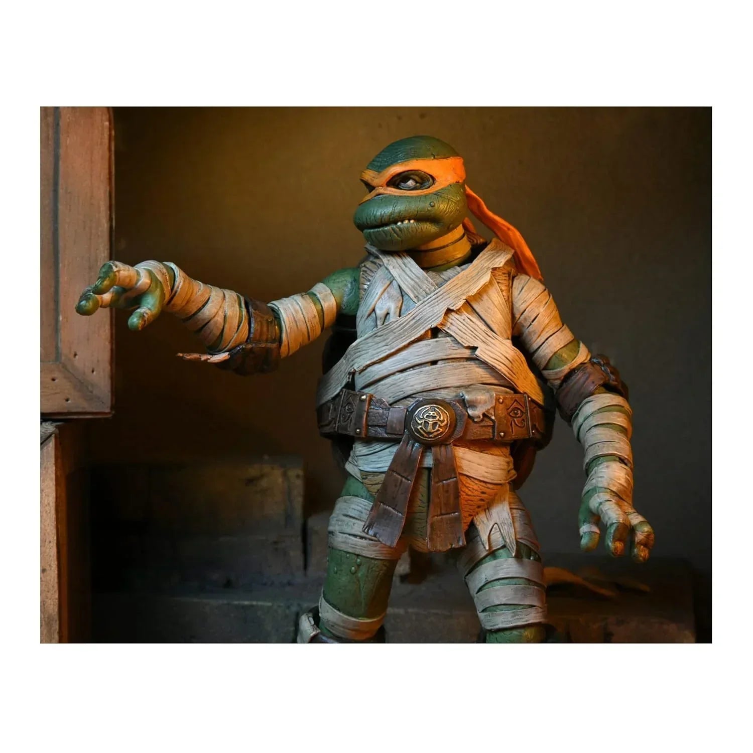Action figure of a ninja turtle with orange mask and bandaged limbs in a dramatic pose