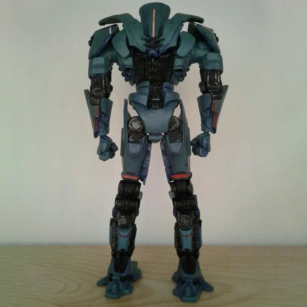 Blue robot action figure standing on wooden surface, back view, detailed joints and armor.