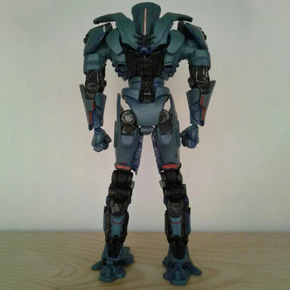 Blue robot action figure standing on wooden surface, back view, detailed joints and armor.