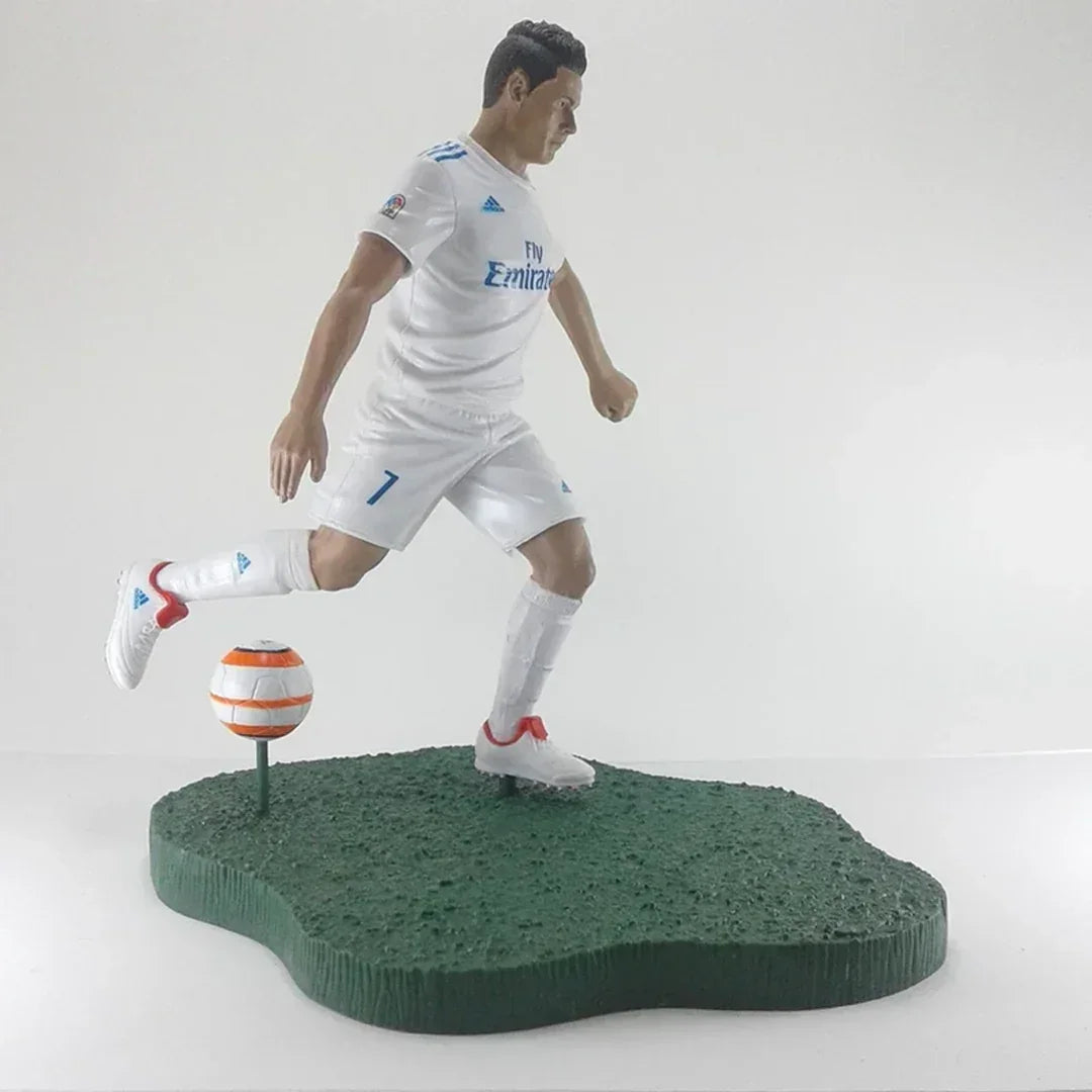 Soccer player action figure in white uniform kicking a ball on green display base
