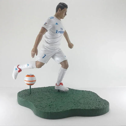 Soccer player action figure in white uniform kicking a ball on green display base