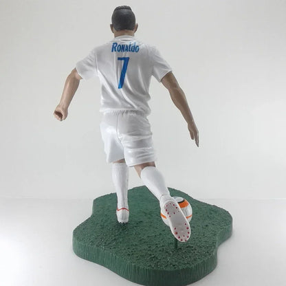 Soccer player figurine in white uniform with number 7, kicking a ball on a green base