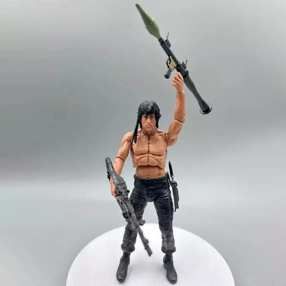 Action figure of muscular man with long black hair holding rocket launcher and rifle, suited for collectors and kids.