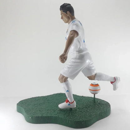 Soccer player action figure in white uniform kicking a ball on green base collectible toy