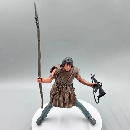 Action figure of rugged man holding a spear and rifle, wearing tattered clothing on display