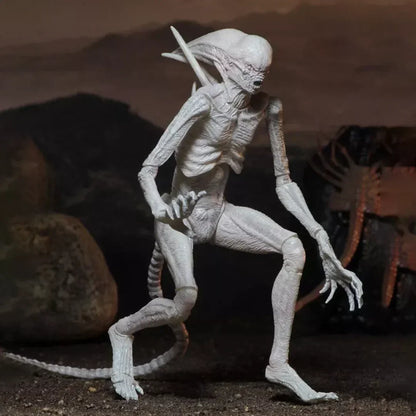 White alien creature action figure with elongated limbs and tail posed on rocky terrain