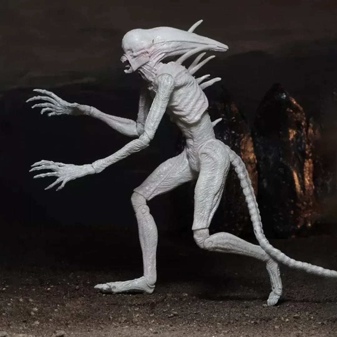 White alien creature action figure with elongated head, long tail, and claws, displayed against a dark background.