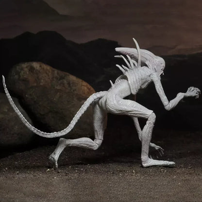 Alien creature action figure with long tail and spines posed on a rocky terrain display.