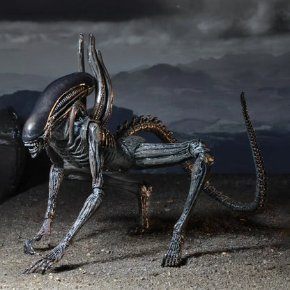 Alien action figure collectible toy with elongated head and tail on dark rocky terrain