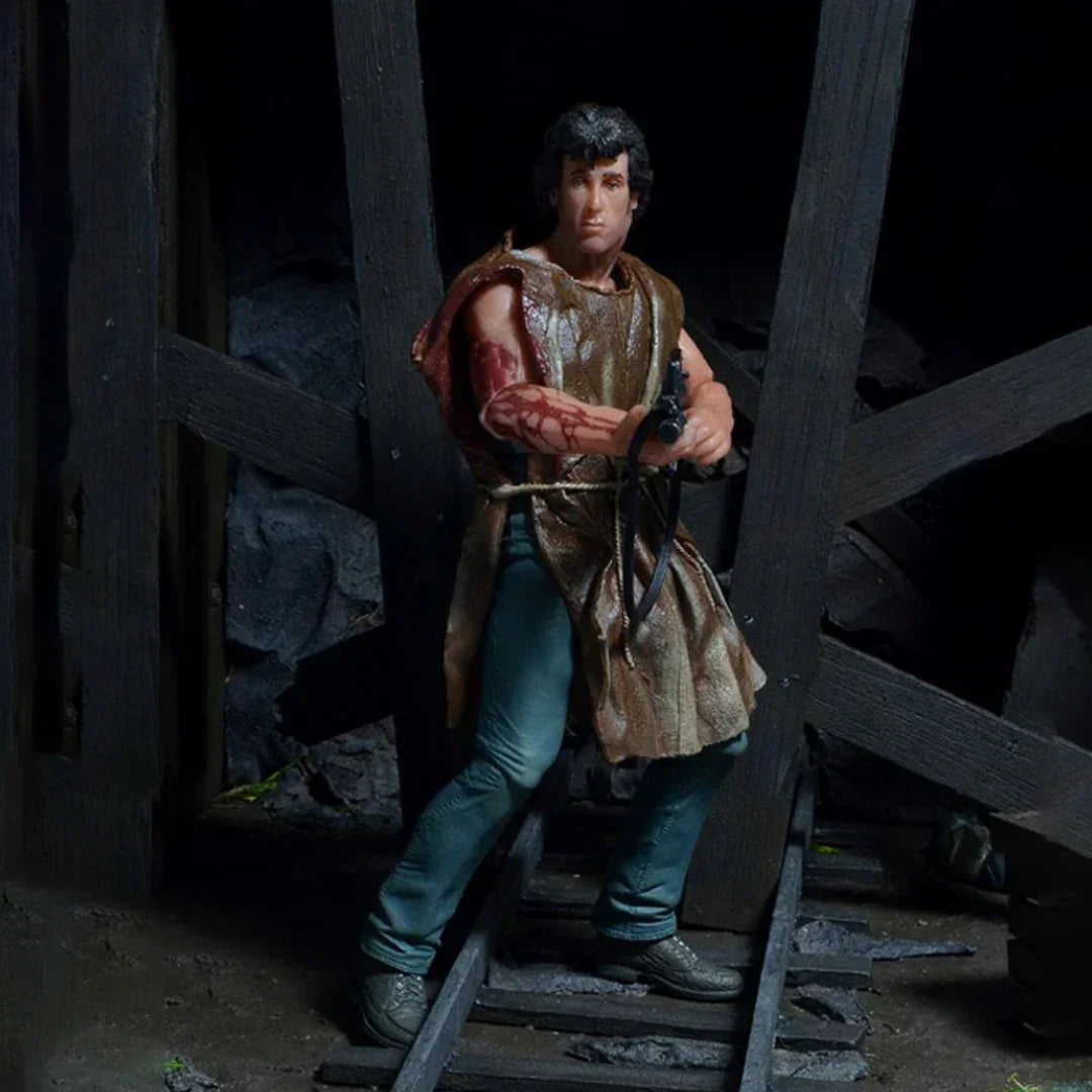 Action figure of a muscular man with curly hair holding a crossbow in a rugged, wooden setting.